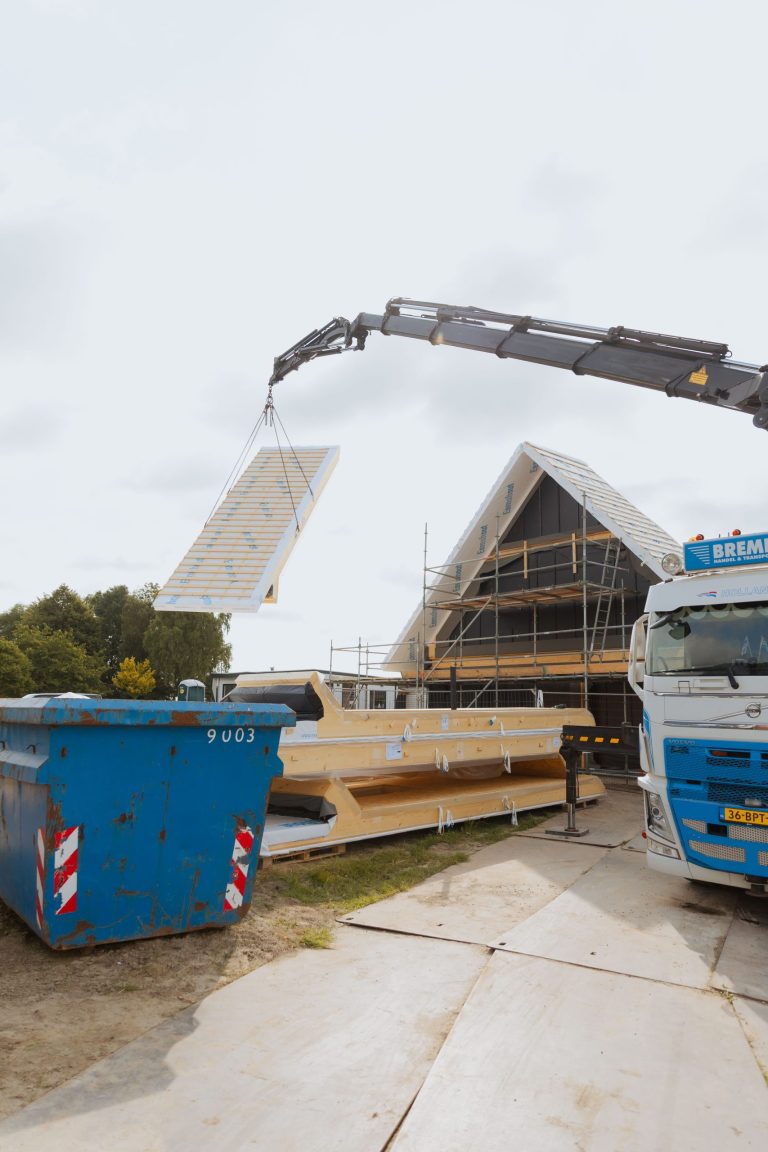 Een dakelement wordt met de kraan op de woning in 't Zandt gelegd